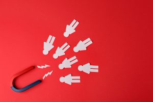 Magnet and paper people on red background